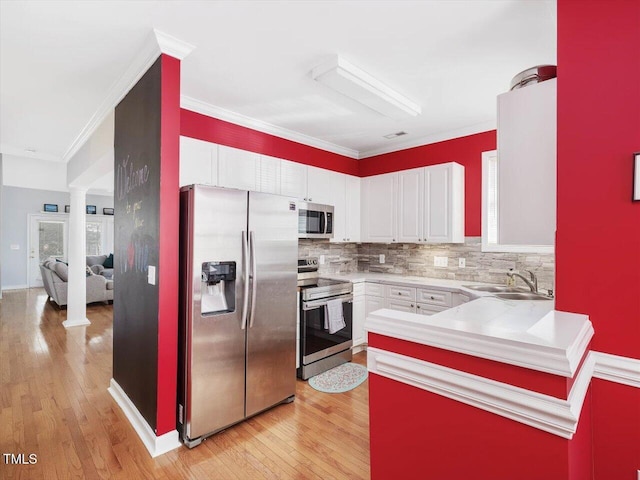 kitchen with sink, stainless steel appliances, white cabinets, and ornate columns