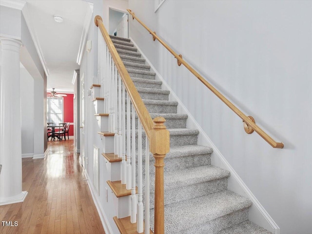 staircase featuring hardwood / wood-style floors, ceiling fan, and ornate columns