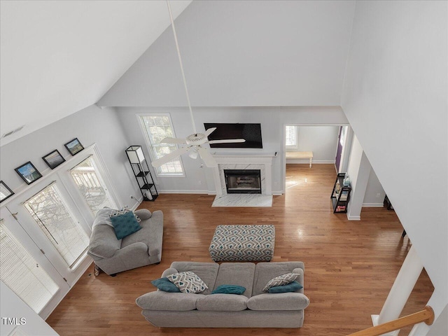 living room with wood-type flooring, a fireplace, and high vaulted ceiling