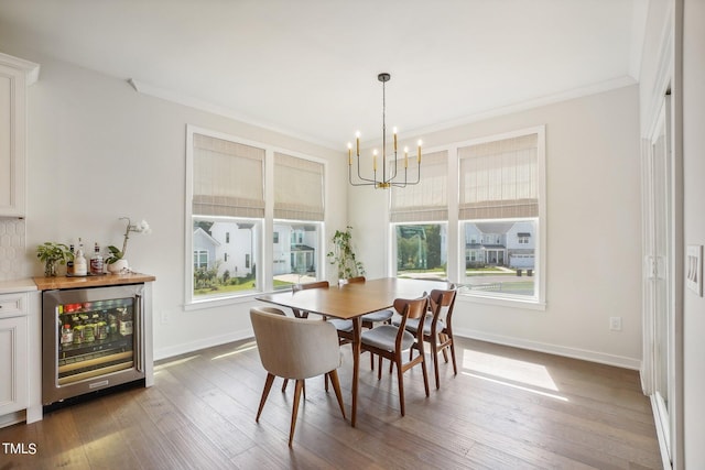 dining room featuring ornamental molding, a chandelier, wine cooler, and dark hardwood / wood-style flooring