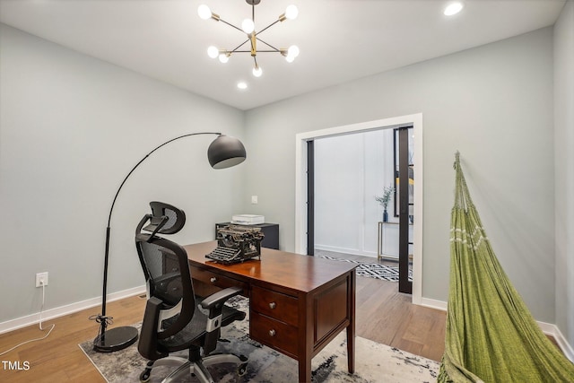 home office with a chandelier and light hardwood / wood-style flooring