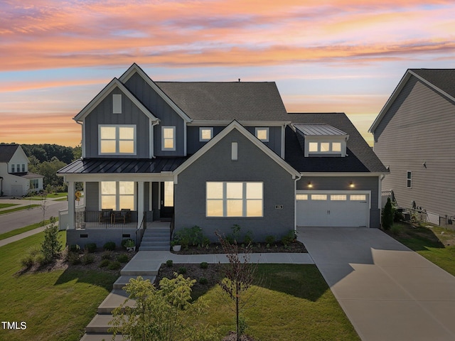 modern inspired farmhouse featuring a yard, covered porch, and a garage