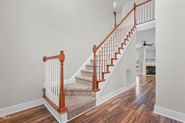 stairs featuring a high ceiling, hardwood / wood-style floors, and ceiling fan