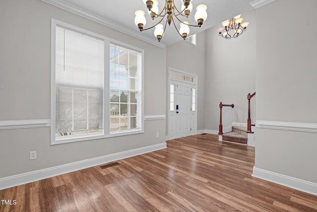 foyer entrance with crown molding, wood-type flooring, and a chandelier