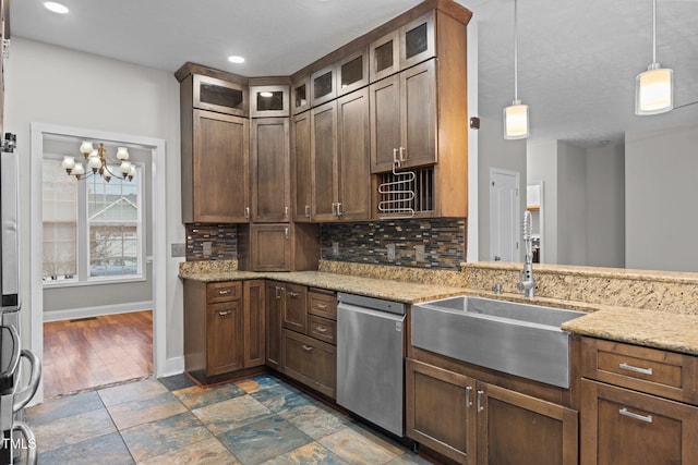 kitchen with pendant lighting, sink, decorative backsplash, stainless steel dishwasher, and light stone countertops