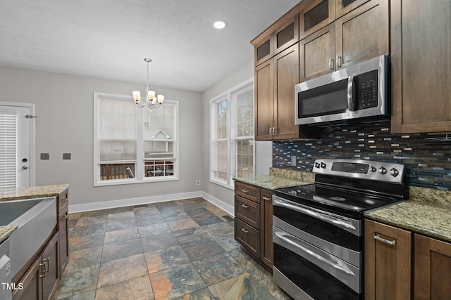 kitchen with pendant lighting, decorative backsplash, a notable chandelier, stainless steel appliances, and light stone countertops