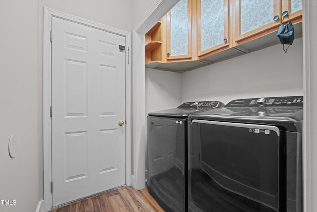 washroom featuring hardwood / wood-style flooring, cabinets, and washer and dryer