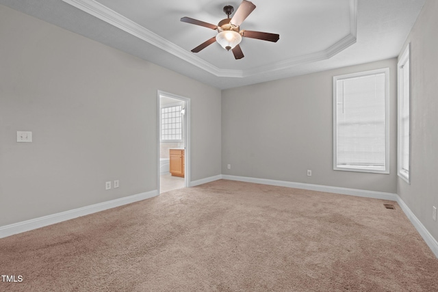 carpeted empty room featuring a raised ceiling, crown molding, and ceiling fan