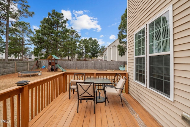 wooden deck featuring a playground and a trampoline