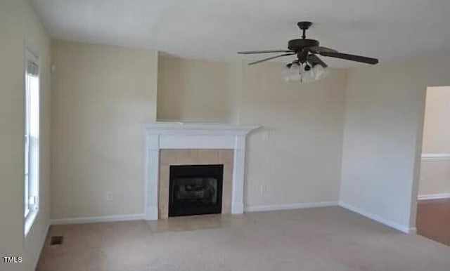 unfurnished living room featuring a tiled fireplace and ceiling fan