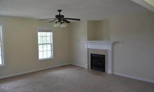 unfurnished living room featuring ceiling fan, a tiled fireplace, and carpet