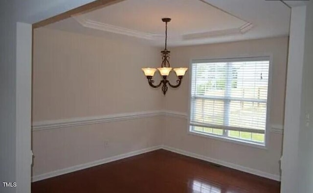 unfurnished room with ornamental molding, dark wood-type flooring, a notable chandelier, and a tray ceiling