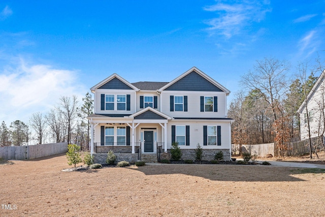 craftsman-style house with stone siding, fence, and a porch