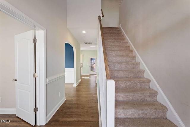 staircase featuring wood finished floors and visible vents