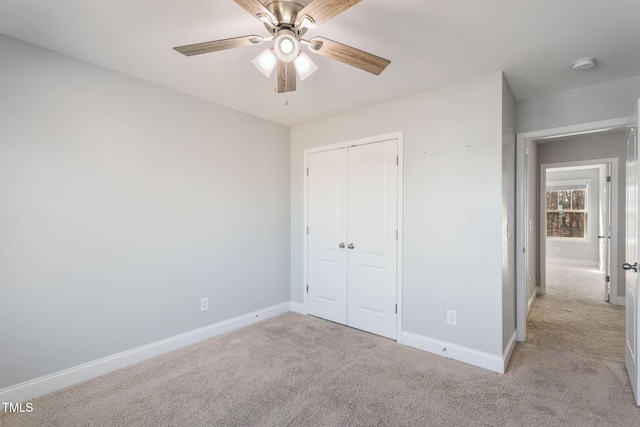 unfurnished bedroom with a ceiling fan, baseboards, a closet, and light colored carpet