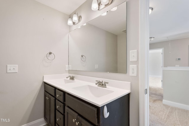 full bath with double vanity, a sink, and baseboards