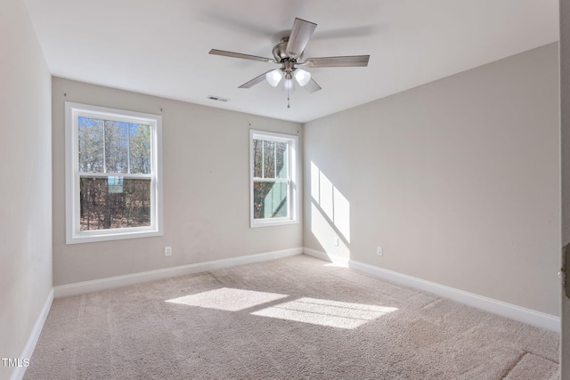 spare room with light carpet, ceiling fan, visible vents, and baseboards