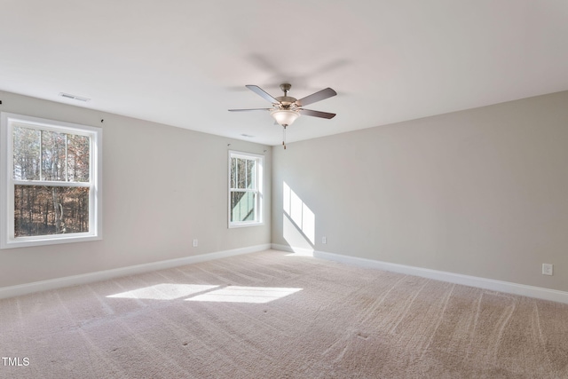 unfurnished room with ceiling fan, visible vents, baseboards, and light colored carpet