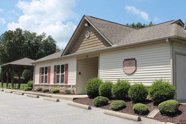 view of front facade with a shingled roof and stone siding