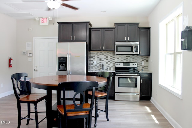 kitchen featuring baseboards, decorative backsplash, stainless steel appliances, and light countertops