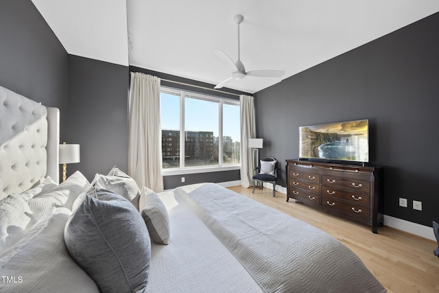 bedroom with ceiling fan, vaulted ceiling, and light wood-type flooring