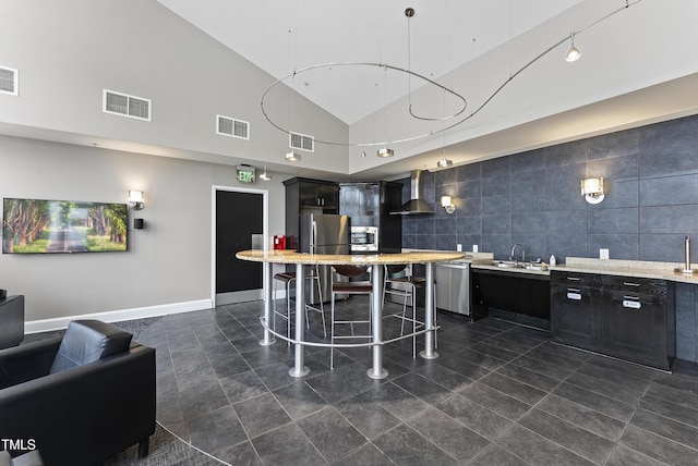 kitchen featuring appliances with stainless steel finishes, decorative light fixtures, sink, a kitchen breakfast bar, and wall chimney exhaust hood