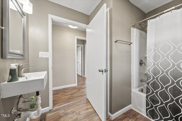 bathroom featuring hardwood / wood-style flooring, shower / bathtub combination with curtain, and a textured ceiling