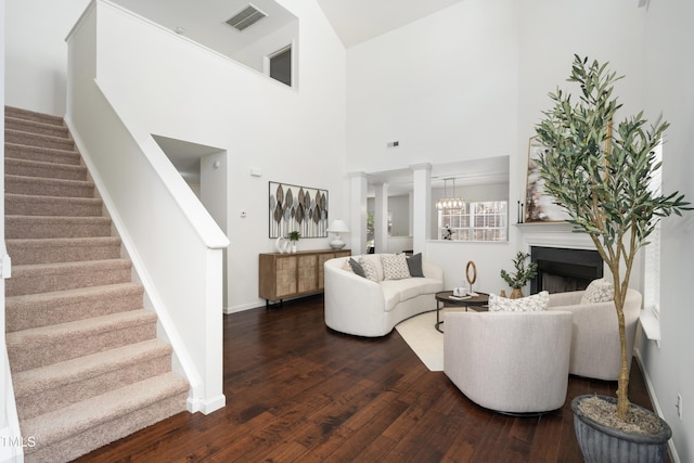 living area featuring stairway, baseboards, dark wood finished floors, a high ceiling, and visible vents