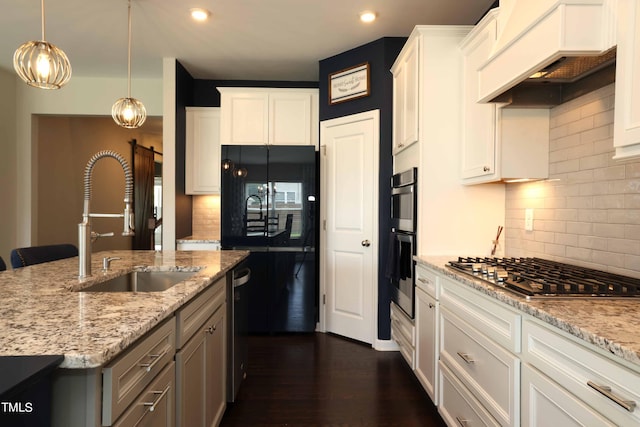 kitchen featuring white cabinetry, light stone counters, hanging light fixtures, custom range hood, and stainless steel appliances