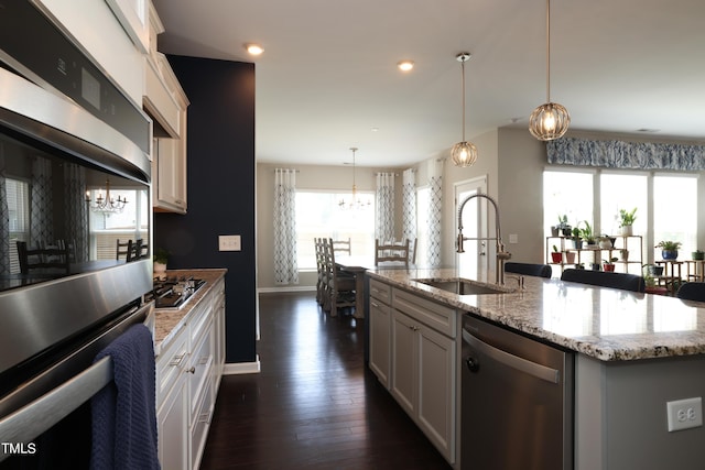 kitchen with white cabinetry, appliances with stainless steel finishes, sink, and a center island with sink