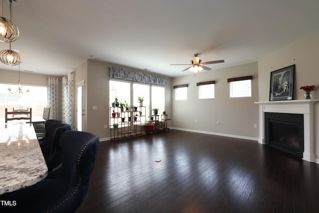 living room with ceiling fan with notable chandelier and dark hardwood / wood-style floors