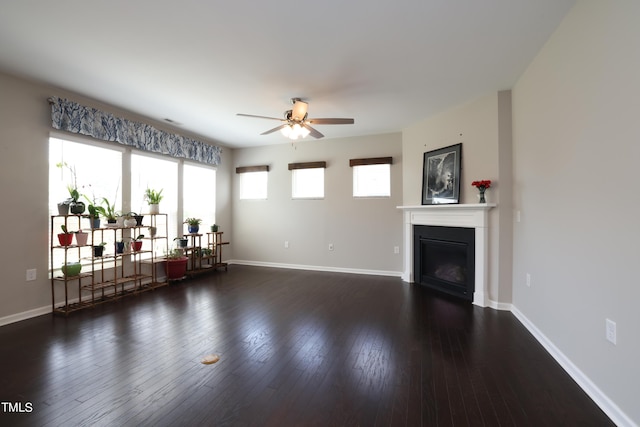 unfurnished living room featuring dark wood-type flooring and ceiling fan