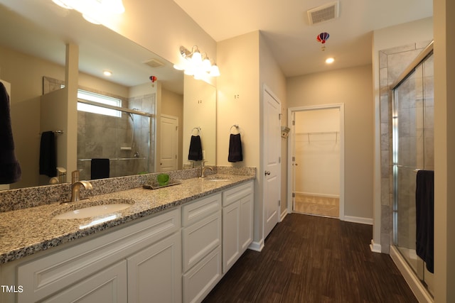 bathroom with wood-type flooring, vanity, and walk in shower