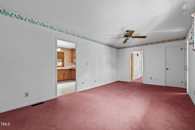 carpeted spare room featuring ceiling fan and a textured ceiling