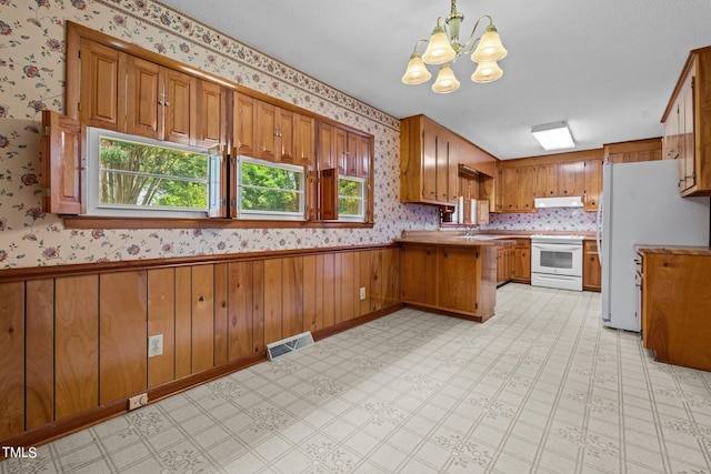 kitchen with sink, white appliances, an inviting chandelier, decorative light fixtures, and kitchen peninsula