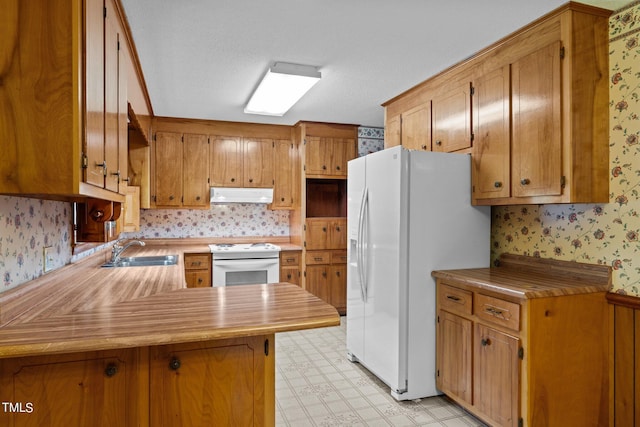 kitchen with white appliances, kitchen peninsula, and sink