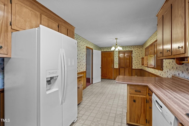 kitchen with white appliances, decorative light fixtures, and a chandelier