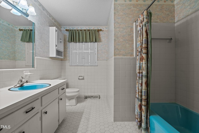 full bathroom featuring tile walls, shower / bath combination with curtain, tile patterned flooring, vanity, and a textured ceiling