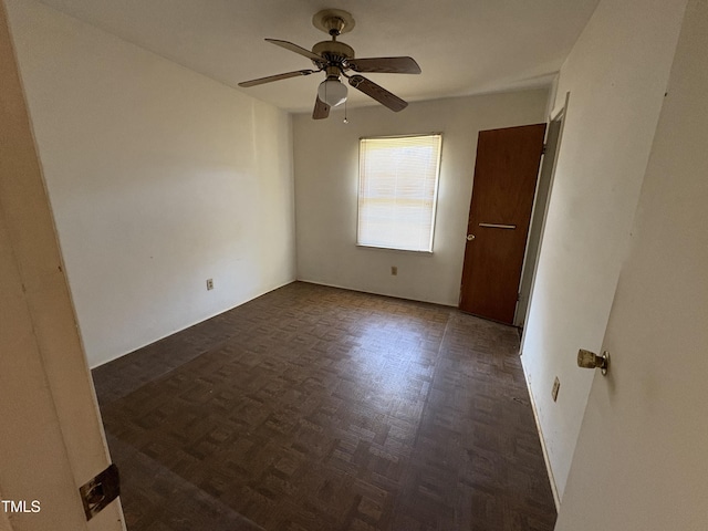 unfurnished room with dark parquet flooring and ceiling fan