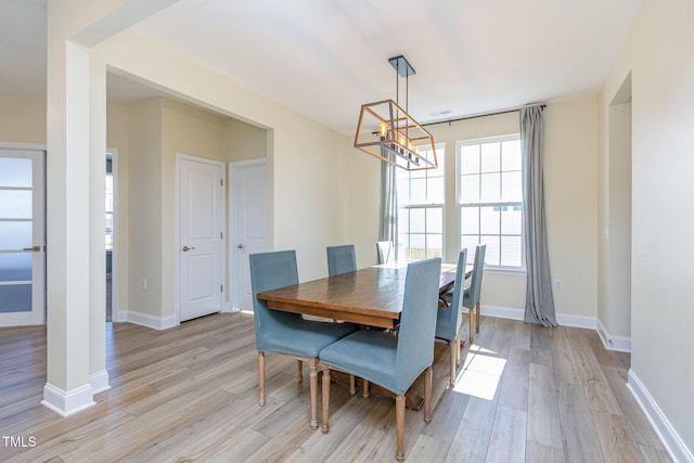 dining room featuring baseboards, light wood-style floors, and an inviting chandelier