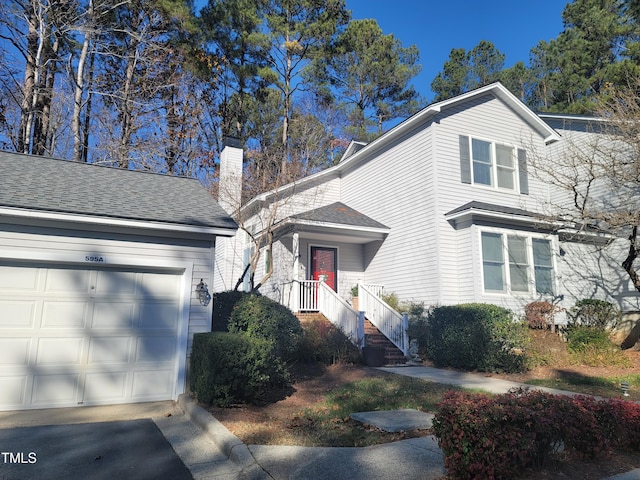 view of front of house with a chimney, a garage, and roof with shingles