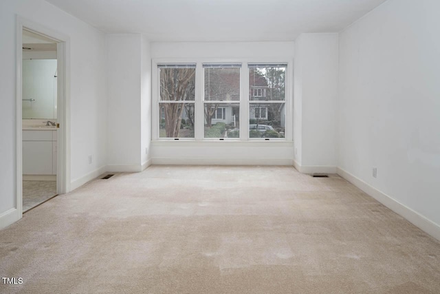 carpeted spare room featuring visible vents and baseboards