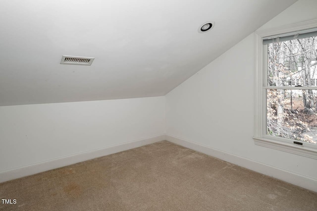 additional living space with visible vents, baseboards, light colored carpet, and lofted ceiling