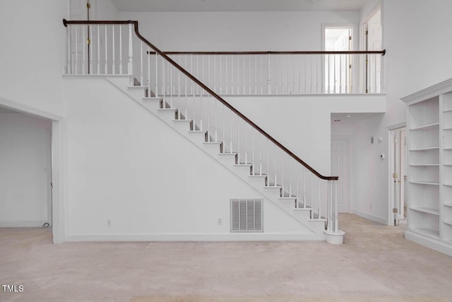 stairway with visible vents, a high ceiling, and carpet floors