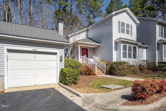 traditional home with aphalt driveway, a garage, a chimney, and a shingled roof