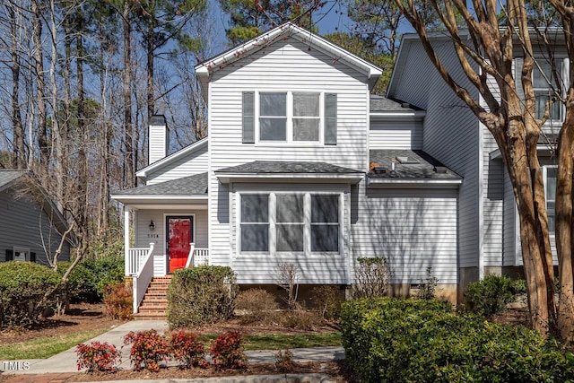 traditional home featuring a shingled roof, a porch, and a chimney