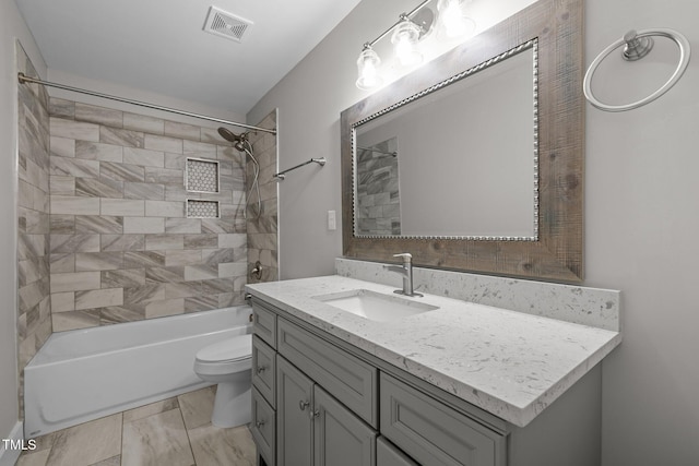 full bathroom featuring vanity, tiled shower / bath combo, and toilet