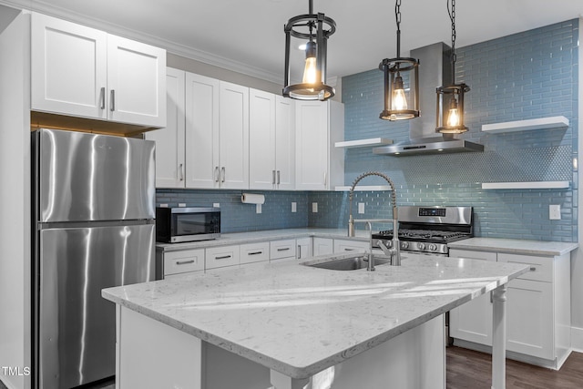 kitchen with light stone counters, stainless steel appliances, a center island with sink, and white cabinets