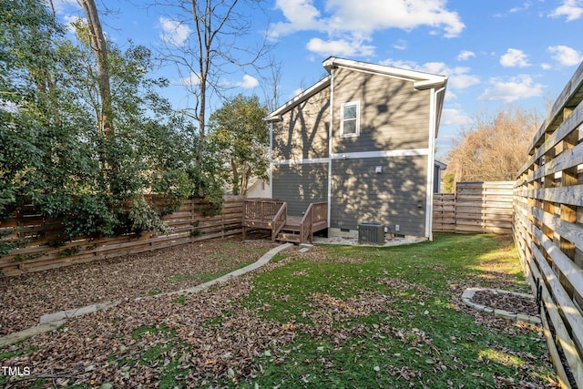 rear view of property featuring a lawn, central air condition unit, and a deck