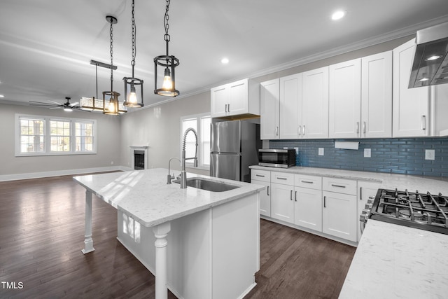 kitchen featuring a kitchen island with sink, sink, light stone countertops, and white cabinets